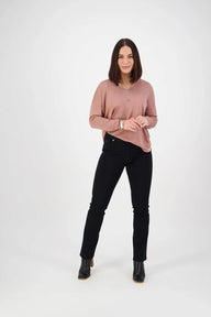 Woman wearing a pink sweater and black jeans on a white background