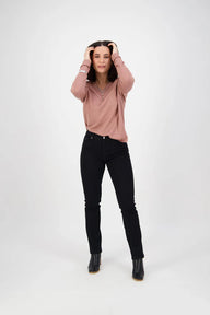 Person wearing a pink sweater and black jeans on a white background