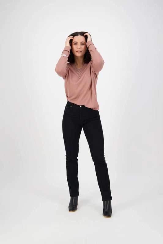 Person wearing a pink sweater and black jeans on a white background