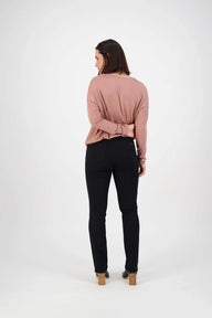 Woman wearing a pink sweater and black jeans on a white background