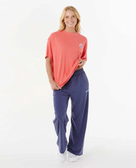 Woman wearing a coral t-shirt and blue pants on a white background
