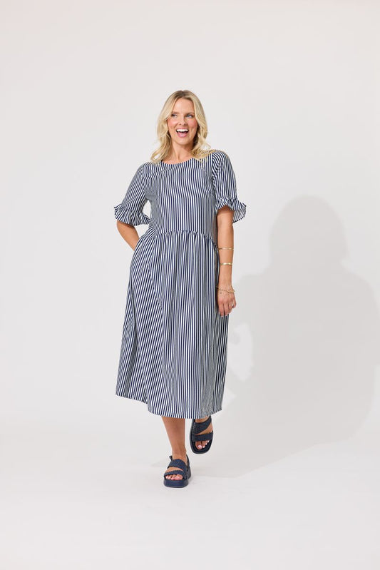 A woman modeling a blue and white vertically striped midi dress with puff sleeves, standing against a plain white studio background.