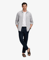 Man wearing a light gray shirt, white undershirt, dark pants, and sandals on a white background