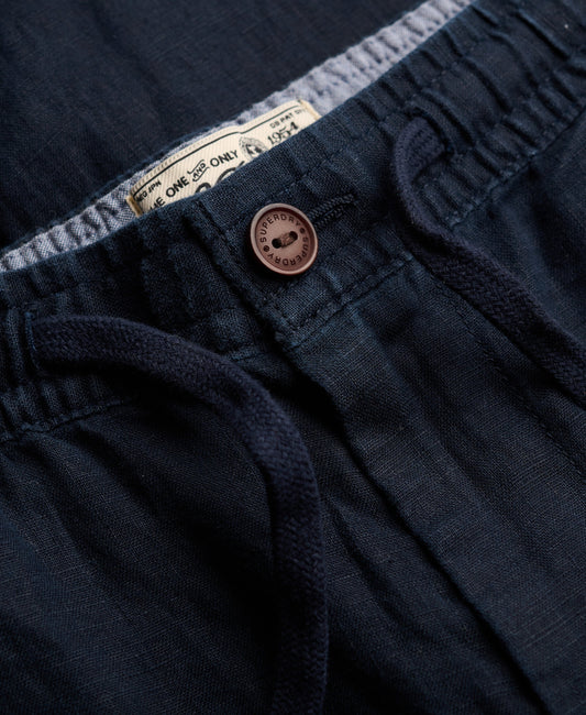 Close-up of navy blue pants with a button and label detail.