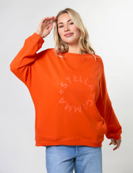 Person wearing an orange sweatshirt with 'Stella + Gemma' logo on a white background