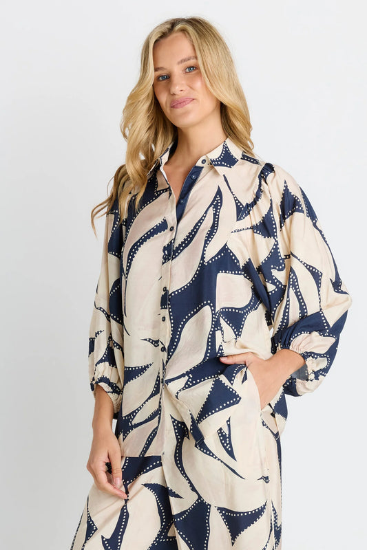 Woman wearing a patterned shirt dress on a plain background