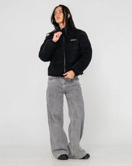 Person wearing a black jacket and gray jeans on a white background