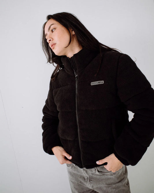Person wearing a black puffer jacket with a brand logo on a white background