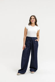 Woman wearing a white top and navy wide-leg pants on a white background