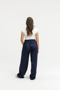Person wearing navy pants and a white top on a white background
