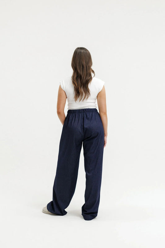Person wearing navy pants and a white top on a white background