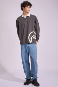 Man wearing a dark gray sweater with a logo, light blue jeans, and black shoes on a white background