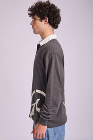 Person wearing a dark gray sweater with a logo on a light gray background