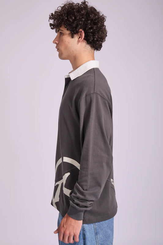 Person wearing a dark gray sweater with a logo on a light gray background