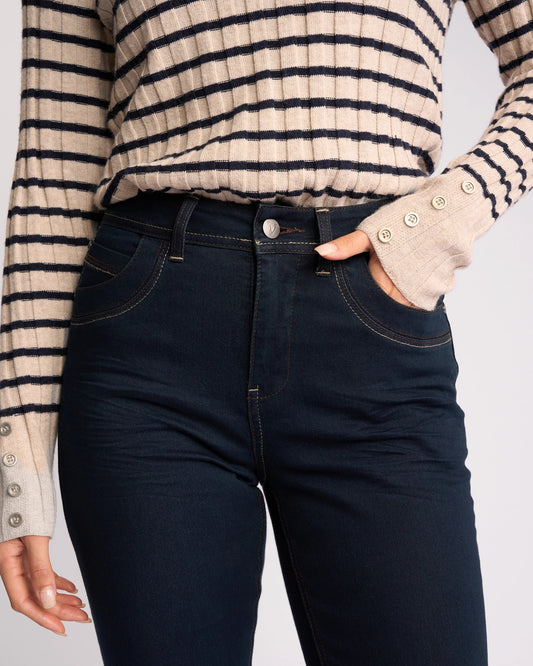 Person wearing navy jeans and a striped sweater with beige gloves on a light gray background
