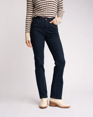 Person wearing dark blue jeans and a striped sweater on a light gray background