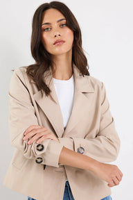 Woman wearing a beige blazer over a white shirt on a plain background