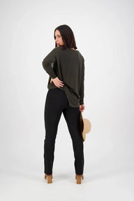 Woman wearing a green sweater and black pants on a white background