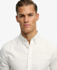 A close-up shot of a man wearing a white long-sleeve button-down shirt against a plain white background.