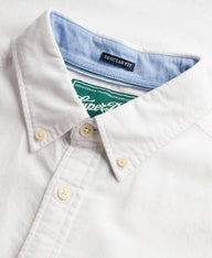 Close-up of a white button-down shirt collar with a light blue inner neck lining and a green Superdry neck label.