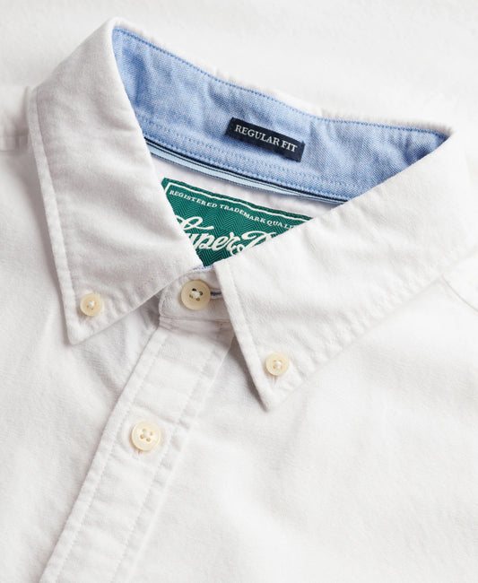 Close-up of a white button-down shirt collar with a light blue inner neck lining and a green Superdry neck label.