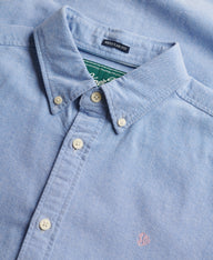 Close-up of a light blue shirt with collar and buttons, featuring a brand label.