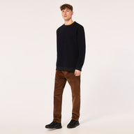 Man wearing a black sweater and brown pants on a white background
