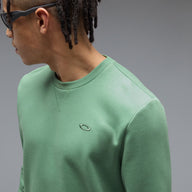 Person wearing a green sweatshirt with a logo on a gray background