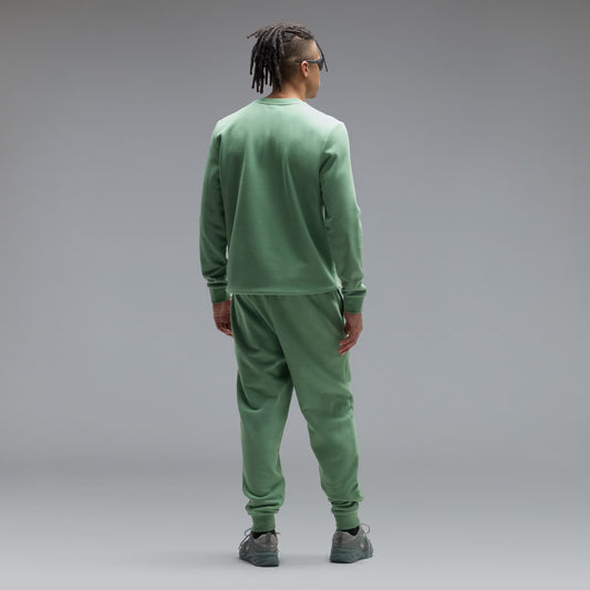 Person wearing a green tracksuit against a gray background