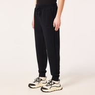 Person wearing black jogger pants and white sneakers on a light beige background