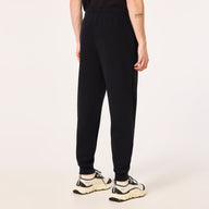 Person wearing black sweatpants and white sneakers on a light beige background