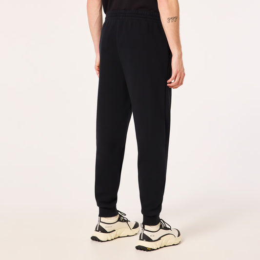 Person wearing black sweatpants and white sneakers on a light beige background
