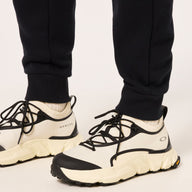 White and black sneakers worn with black pants on a light background