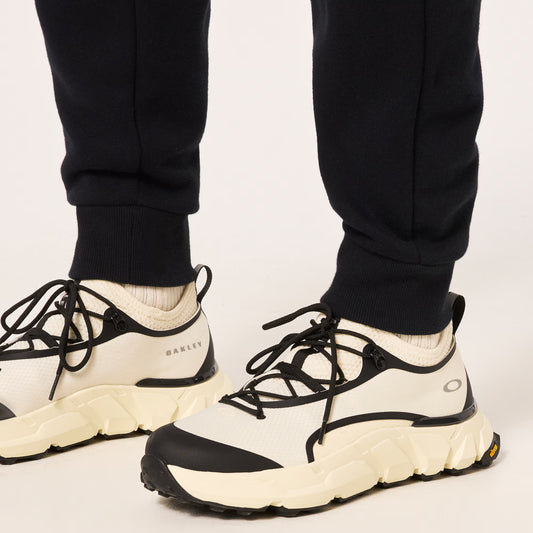 White and black sneakers worn with black pants on a light background
