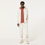 Man wearing a white hoodie, striped shirt, and pants on a white background