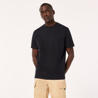 Man wearing a black t-shirt and beige pants on a white background