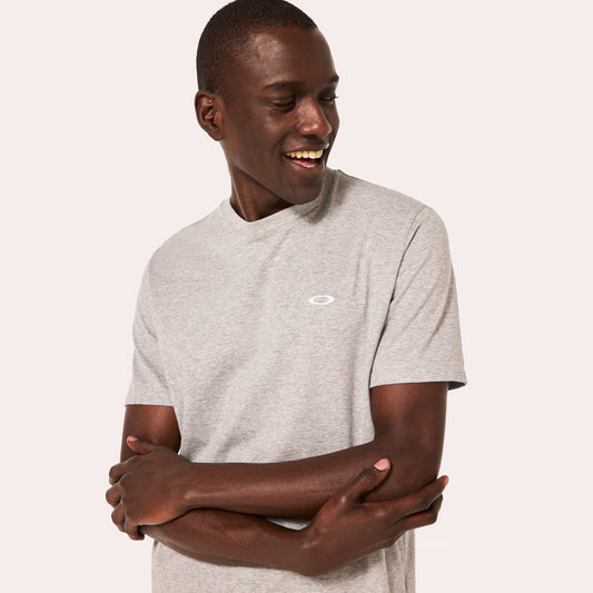 Man wearing a gray t-shirt with a small logo on a plain background