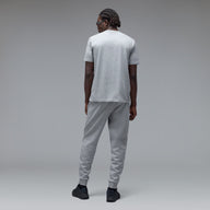 A man wearing a light gray heather t-shirt and matching jogger sweatpants, shown from the back against a neutral gray studio background.