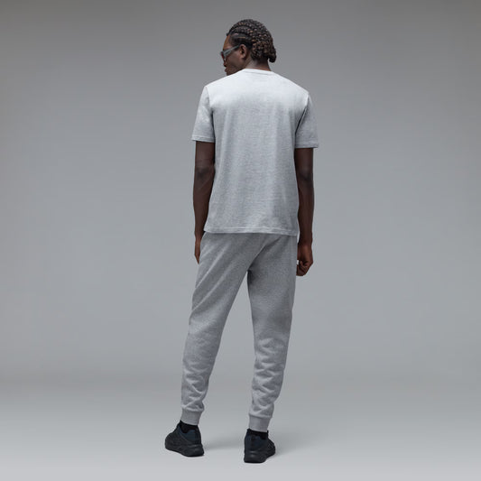 A man wearing a light gray heather t-shirt and matching jogger sweatpants, shown from the back against a neutral gray studio background.