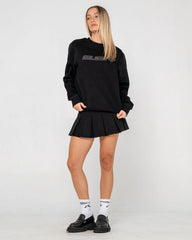Person wearing a black oversized sweatshirt and skirt with visible branding on a white background