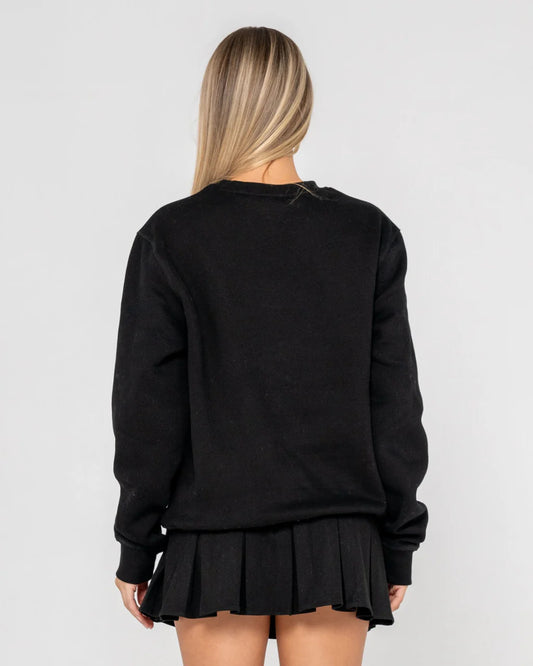 Person wearing a black sweatshirt and pleated skirt on a plain background