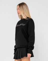 Woman wearing a black sweatshirt with 'rusty' text and a black skirt on a white background