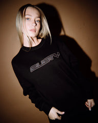 Person wearing a black sweatshirt with 'Rusty' logo against a brown background