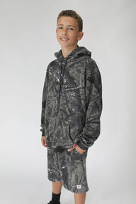 Person wearing a camouflage hoodie and pants on a white background