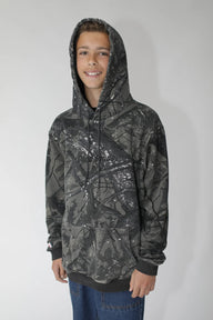 Person wearing a dark camouflage hoodie with a brand logo on a white background