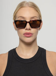 Woman wearing a black sleeveless top with a plain background