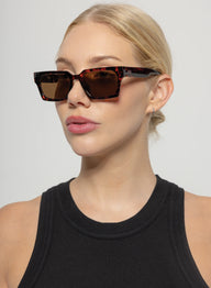 Woman wearing a pair of sunglasses with a plain background