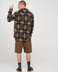 Person wearing a plaid shirt and brown shorts on a white background