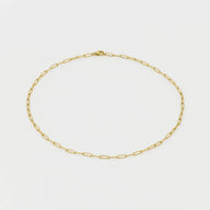 Gold chain necklace on a light gray background