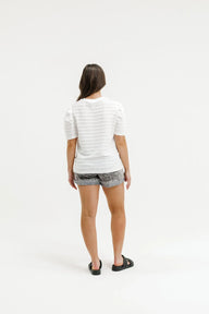 Person wearing a striped shirt and shorts on a white background